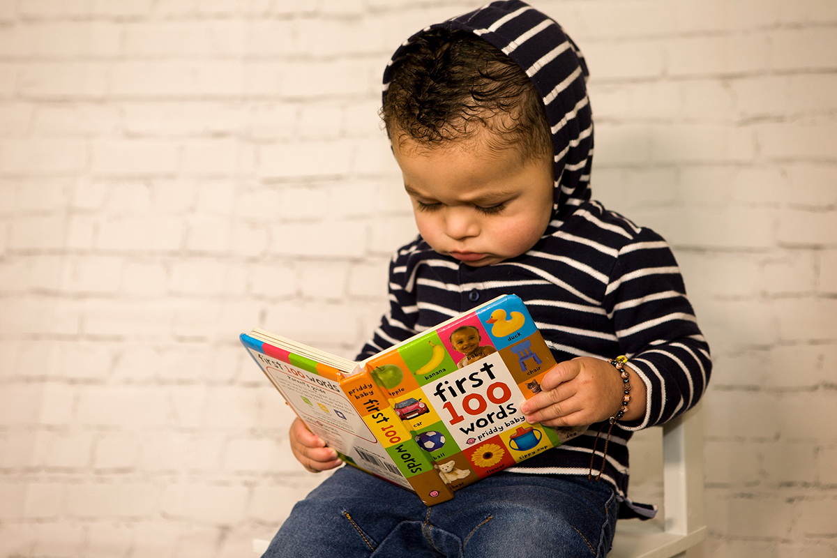 Young boy reading first words book.